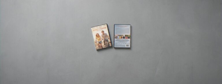 Voor- en achterkant van een dvd-hoes op een grijze ondergrond; de achterkant met de samenvatting ligt scherp